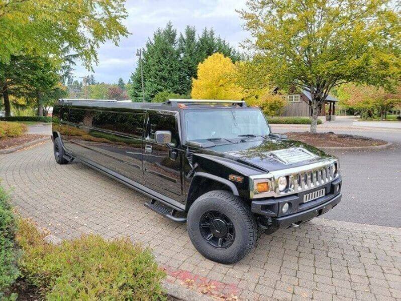 Black Hummer H2 stretch limousine with autumn trees